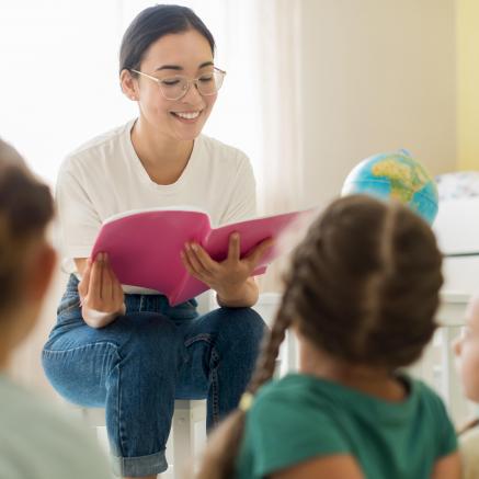 Woman with glasses reading to a group of children