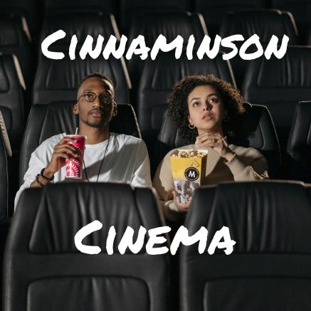 Two people are sitting in a movie theater with snacks.