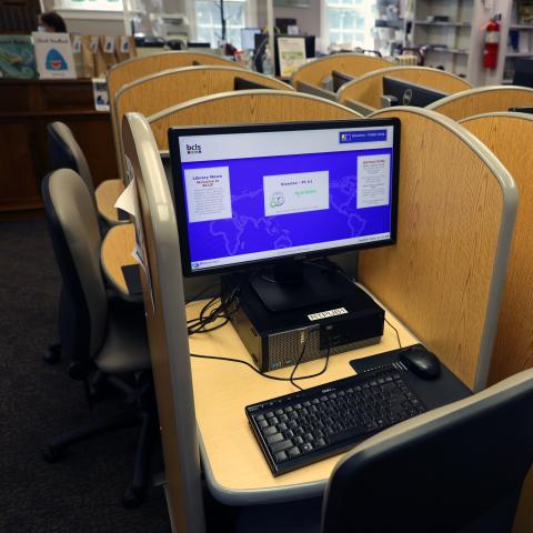 A computer sits in a study carrel, ready for use by a patron.