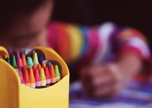 A child colors with crayons
