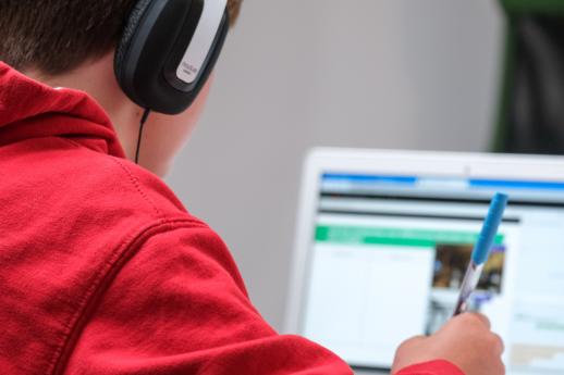 child in red hoodie studying at a computer