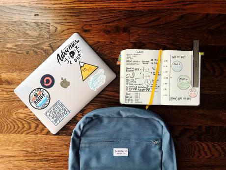 a backpack laptop and notebook on a table