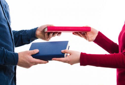 two people passing books to eachother