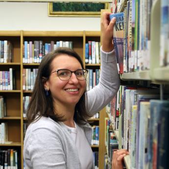 Caitlin, branch manager at the Bordentown Library, pulls a book off the shelf.