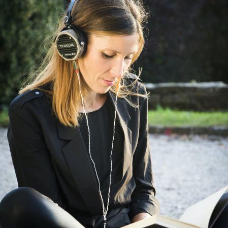 Woman with book and heaphones reading audio book