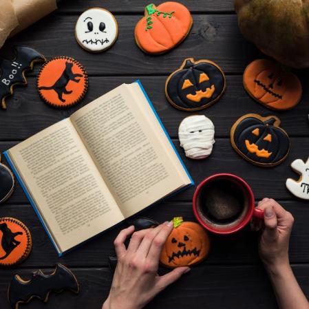 A book open on a table surrounded by Halloween decorated cookies