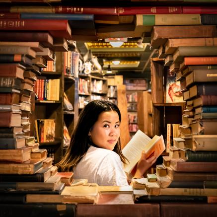 Woman reading a book surrounded by books