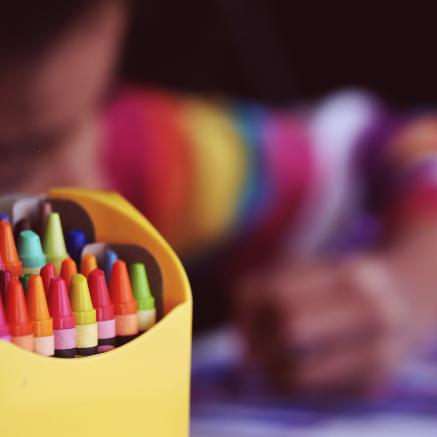 A child colors with crayons