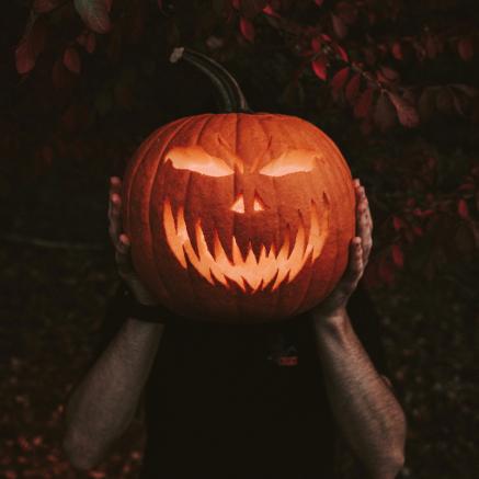 Two hands hold up a Jack-o-Lantern