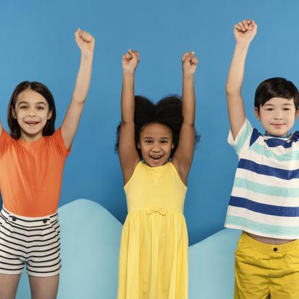 Three kids with their arms up with a blue background