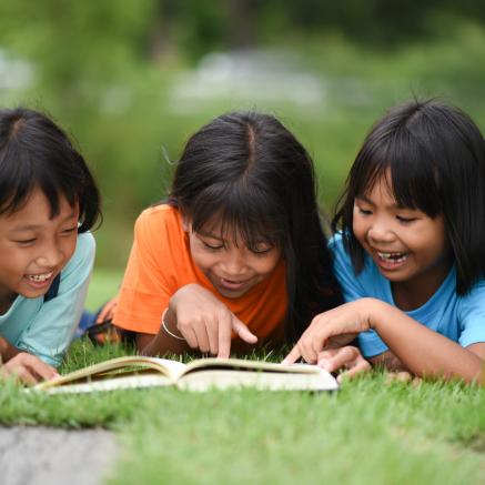 A group of children reading outside in the grass