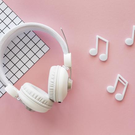 White headphones on pink background with white music notes
