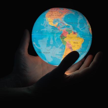 Hands hold an illuminated globe.