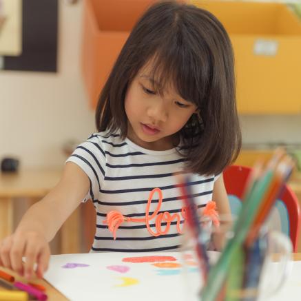 girl drawing with color pencils in preschool