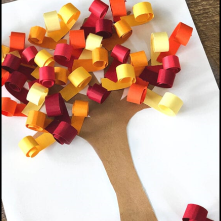 A picrture of a tree features colorful paper, curled and glued to it to simulate leaves. 