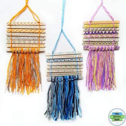 Popsicle sticks are strung together with colorful yarn to simulate a tapestry.