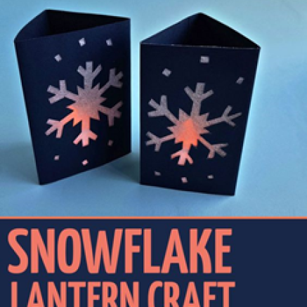 A lantern made out of folded paper with cut out snowflake shapes