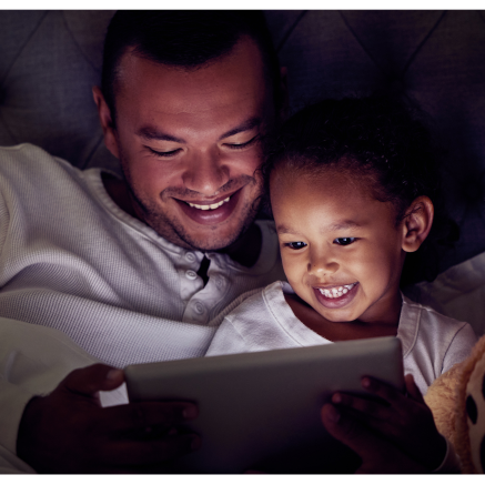 Father and daughter read a story together on a tablet.