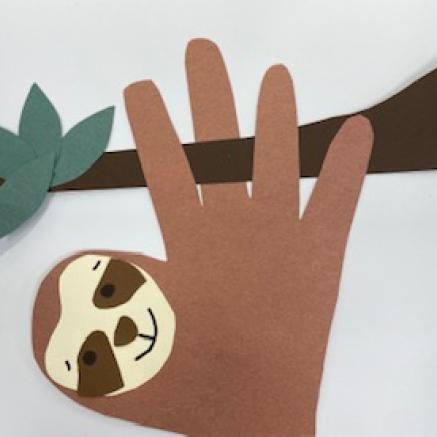 handprint paper cut out made into a sloth hanging from a tree branch-kid craft