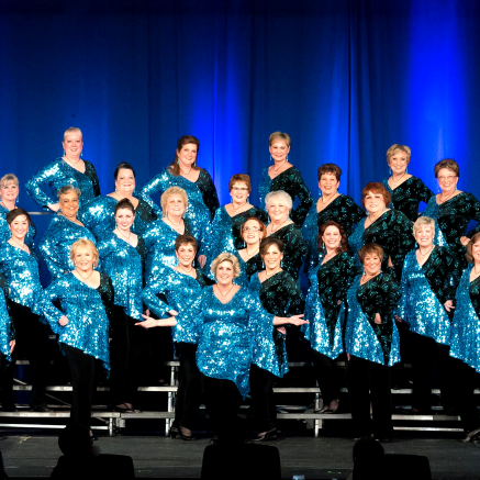 Jersey Sound Chorus poses on risers in sequined light blue tops and black pants