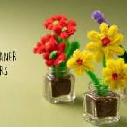 picture of small flowers made of pipe cleaners. One has yellow flowers in a small vase and the other is red flowers.