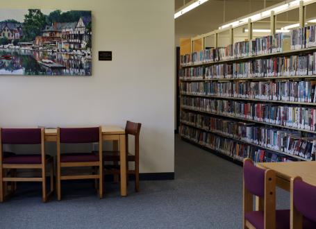 A painting is seen on the wall of the Evesham Library, next to some shelving with books