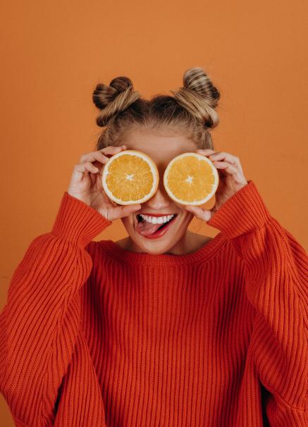 A woman holds up oranges in front of her eyes