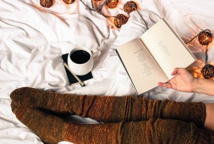Coffee cup in bed with book and cozy socks