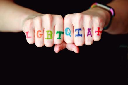 Hands feature the letters LGBTQIA+ on each finger
