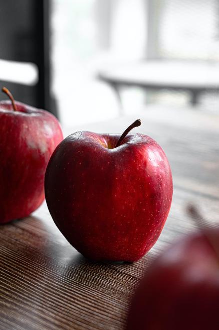 A red apple sits on a table, ready to be picked up and eaten