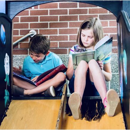 A boy and girl are sitting and reading.