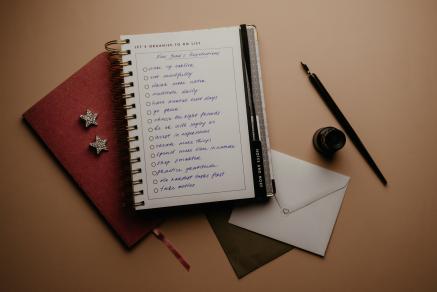 A red and white notebook with New Year's Resolutions written in script handwriting