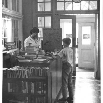 A student checks out books at the County Library, 1950s