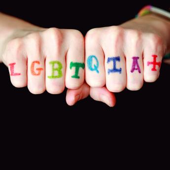 Hands feature the letters LGBTQIA+ on each finger