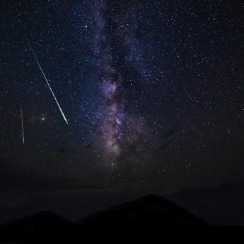 Two meteors fall in the starry night sky