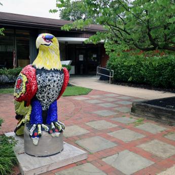 An eagle sits on a stand, in front of the Cinnaminson Library.