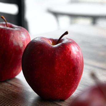 A red apple sits on a table, ready to be picked up and eaten