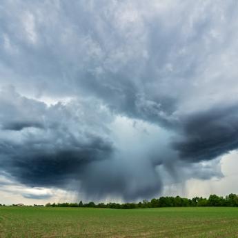 Storm cloud over a green field.