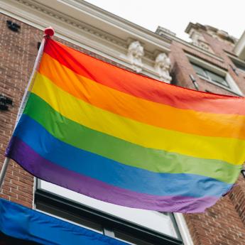 a rainbow flag waves in front of a building.