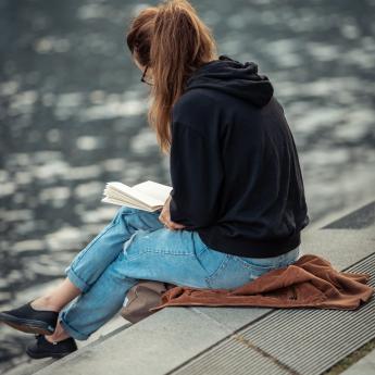 Woman reading on dock of lake.