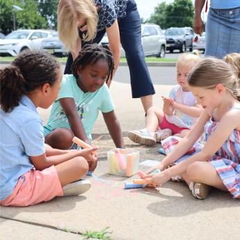 Photo of children drawing on the ground with sidewalk chalk